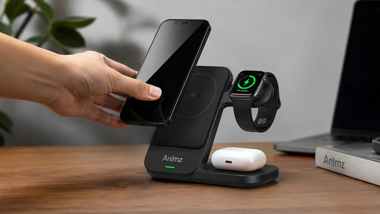 A hand placing an iPhone onto the angled charging pad of the Anlmz 3 in 1 charging station while an Apple Watch and AirPods case are already charging