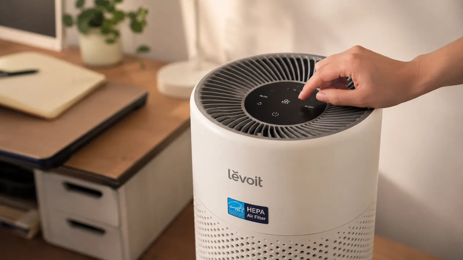 Hand adjusting the fan speed dial on top of the Levoit air purifier
